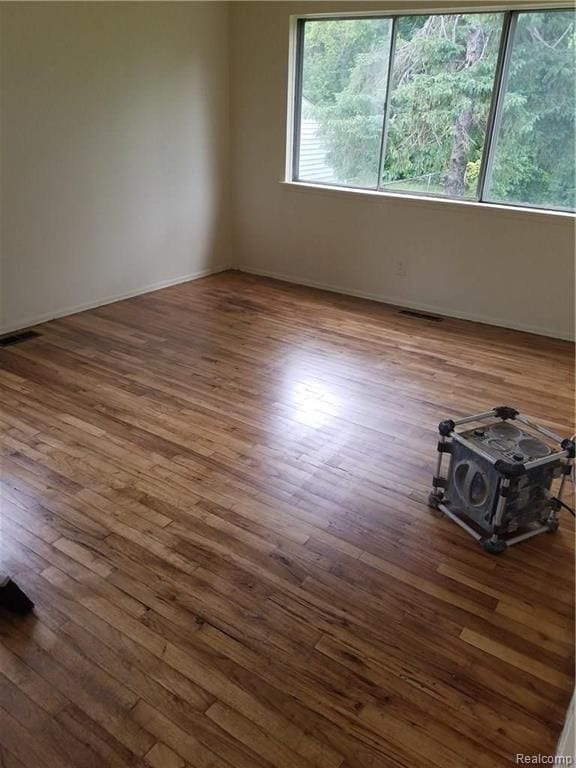 spare room featuring visible vents, a wood stove, and wood finished floors