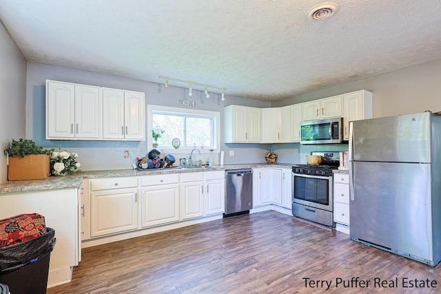 kitchen featuring stainless steel appliances, dark wood finished floors, white cabinets, a sink, and a textured ceiling