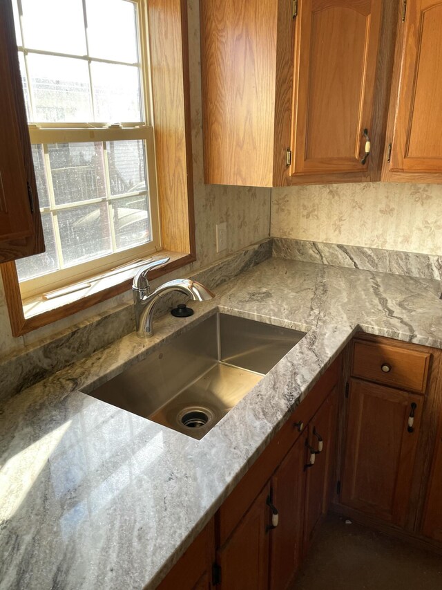 3947 W Jefferson Ave, Trenton, MI 48183 - kitchen featuring brown cabinetry, light stone countertops, and a sink