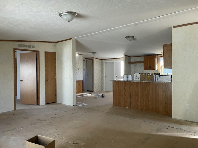 3947 W Jefferson Ave, Trenton, MI 48183 - kitchen with brown cabinetry, visible vents, a peninsula, ornamental molding, and a textured ceiling