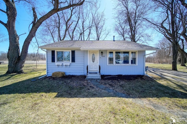 view of front of house with a front yard, driveway, and roof with shingles