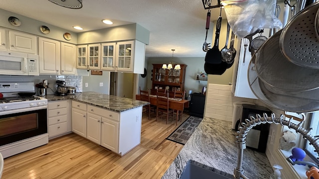 70255 51st St, Lawrence, MI 49064 - kitchen with white cabinets, an inviting chandelier, light wood-style floors, white appliances, and a peninsula