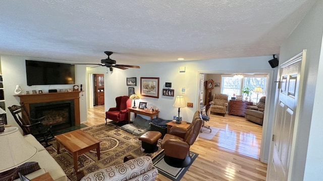70255 51st St, Lawrence, MI 49064 - living area featuring a textured ceiling, a fireplace with flush hearth, ceiling fan, and light wood-type flooring