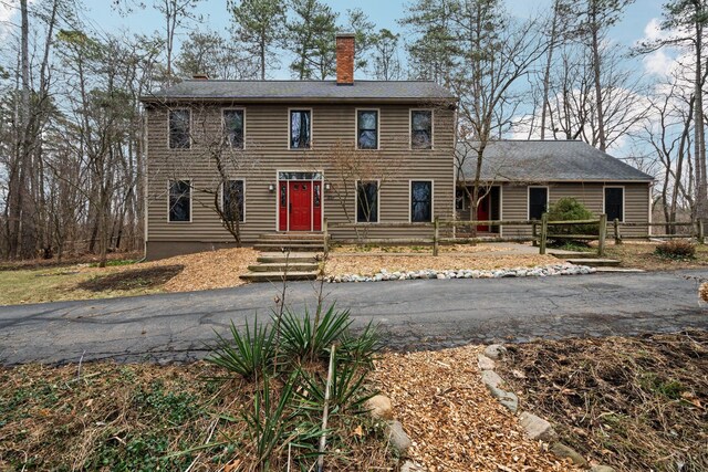 colonial home with entry steps, fence, and a chimney