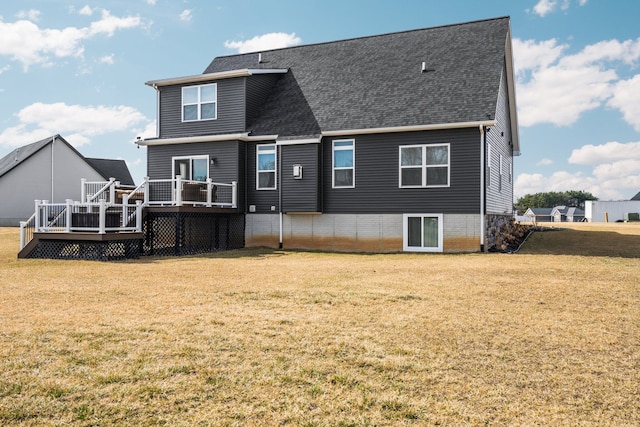 rear view of property featuring a wooden deck, a shingled roof, and a yard
