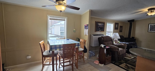 3867 Joseph St, Wellston, MI 49689 - dining room with a ceiling fan, a wood stove, light wood-style flooring, and a textured ceiling