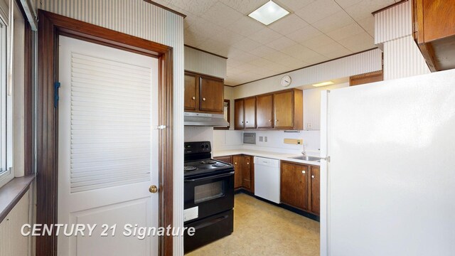 308 S Elm St, Saginaw, MI 48602 - kitchen featuring under cabinet range hood, light floors, light countertops, brown cabinets, and white appliances