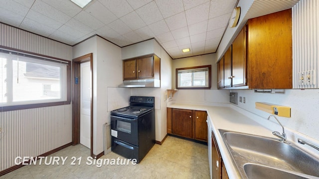 308 S Elm St, Saginaw, MI 48602 - kitchen with brown cabinets, under cabinet range hood, a sink, black range with electric cooktop, and light countertops