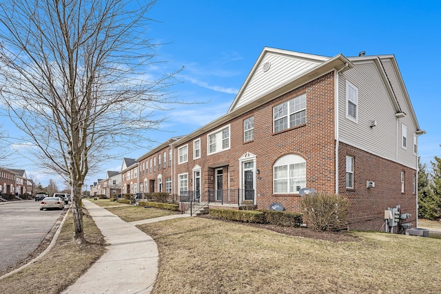 view of side of property featuring a yard, brick siding, and a residential view
