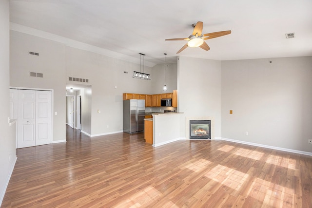 unfurnished living room with light wood-style flooring, a ceiling fan, and visible vents