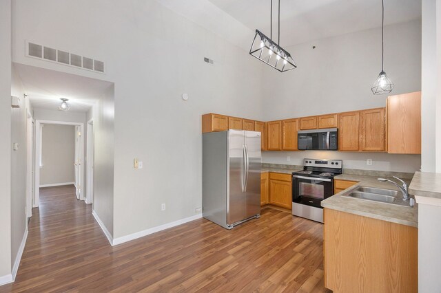 kitchen with wood finished floors, baseboards, visible vents, a sink, and stainless steel appliances