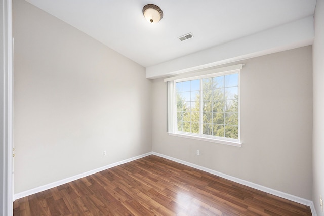 spare room featuring visible vents, baseboards, and dark wood finished floors