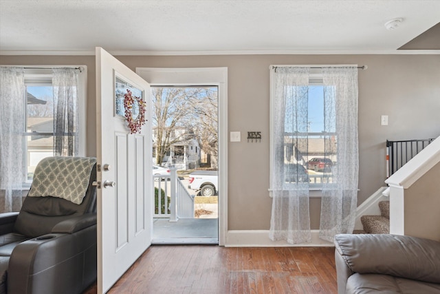 doorway to outside with a wealth of natural light, stairway, wood finished floors, and baseboards