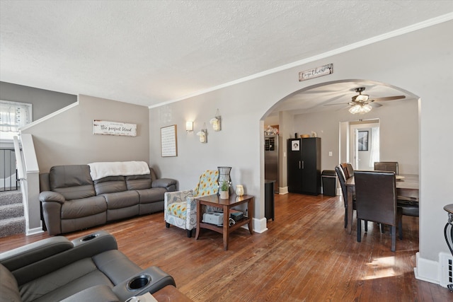 living area featuring arched walkways, a textured ceiling, a ceiling fan, and hardwood / wood-style floors