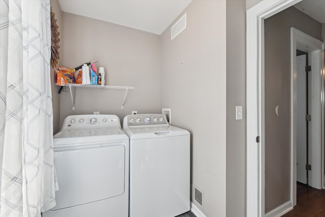 clothes washing area with dark wood-style floors, baseboards, separate washer and dryer, and visible vents