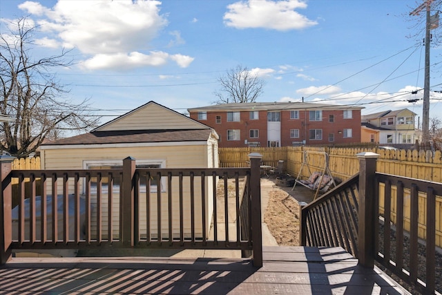 deck with a fenced backyard, an outdoor structure, and a residential view