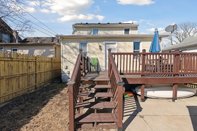 rear view of house featuring fence and a deck