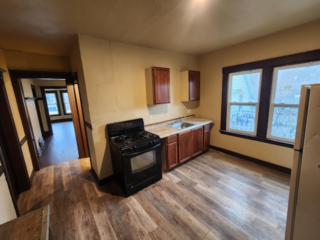 3491 Garland St, Detroit, MI 48214 - kitchen with wood finished floors, freestanding refrigerator, a sink, light countertops, and black range with gas cooktop