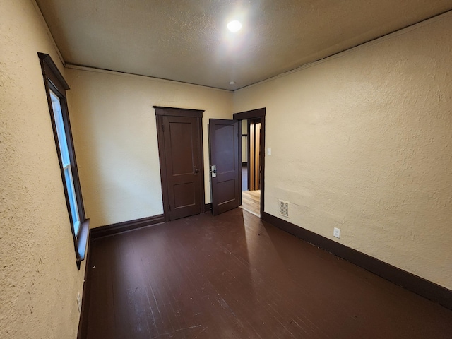 3491 Garland St, Detroit, MI 48214 - unfurnished room with dark wood-type flooring, baseboards, visible vents, and a textured wall