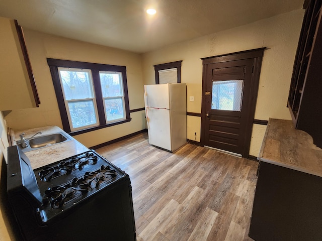 3491 Garland St, Detroit, MI 48214 - kitchen featuring a sink, freestanding refrigerator, gas stove, light wood finished floors, and a healthy amount of sunlight