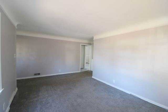 spare room featuring visible vents, dark colored carpet, and baseboards
