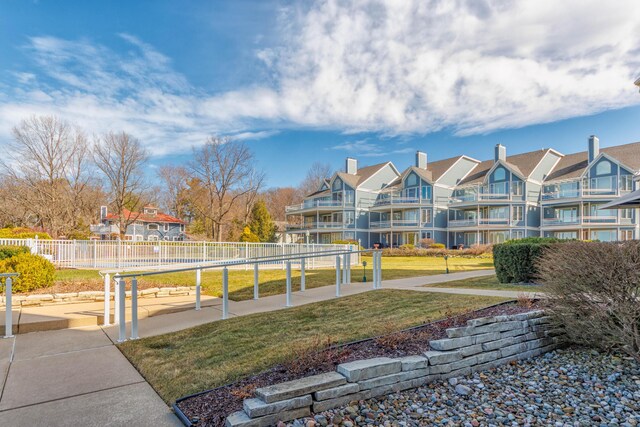 view of property's community with a residential view, a lawn, and fence