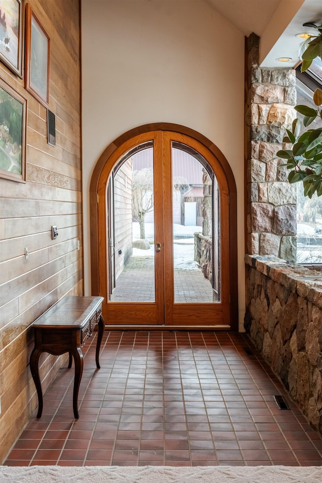 doorway to outside with arched walkways, visible vents, french doors, and a towering ceiling