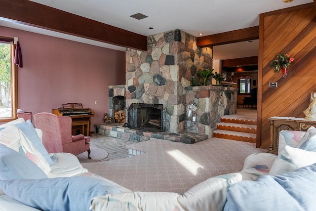 living area with a stone fireplace, beamed ceiling, and wooden walls