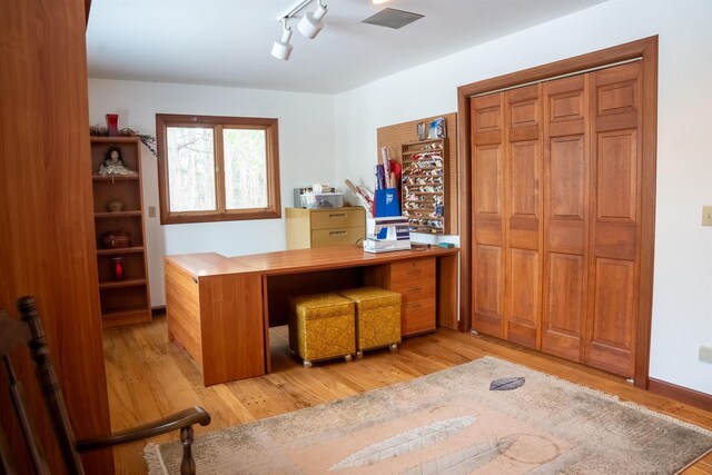 office area with rail lighting and light wood-type flooring