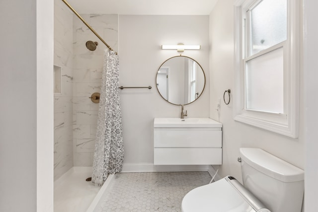 full bath with toilet, vanity, baseboards, and a tile shower