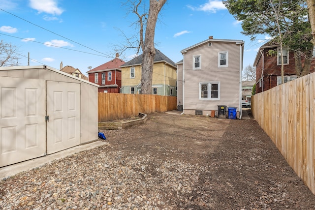 back of property with an outbuilding, a storage unit, a fenced backyard, and a residential view