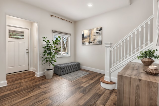 foyer featuring baseboards, wood finished floors, and stairway