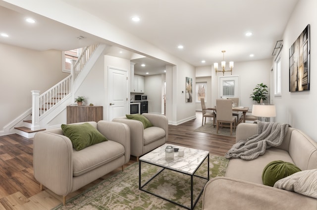 living room with stairs, recessed lighting, an inviting chandelier, baseboards, and wood finished floors