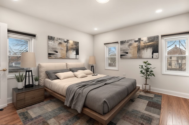 bedroom featuring baseboards, wood finished floors, and recessed lighting