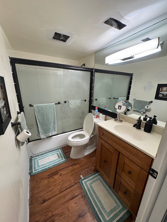 bathroom featuring vanity, toilet, wood finished floors, and combined bath / shower with glass door