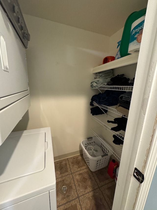 laundry room with tile patterned floors, stacked washer and clothes dryer, and laundry area