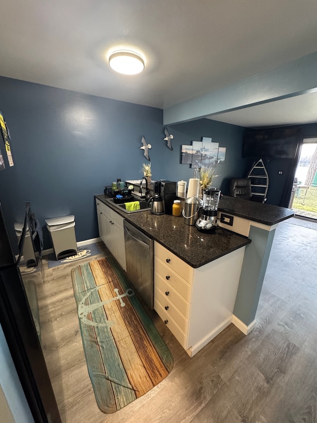 kitchen with wood finished floors, white cabinetry, dark stone counters, a sink, and dishwasher