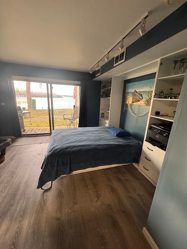 bedroom with visible vents, wood finished floors, and access to outside