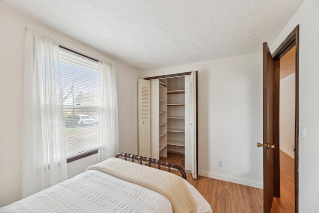 bedroom with light wood-type flooring, a textured ceiling, and multiple windows