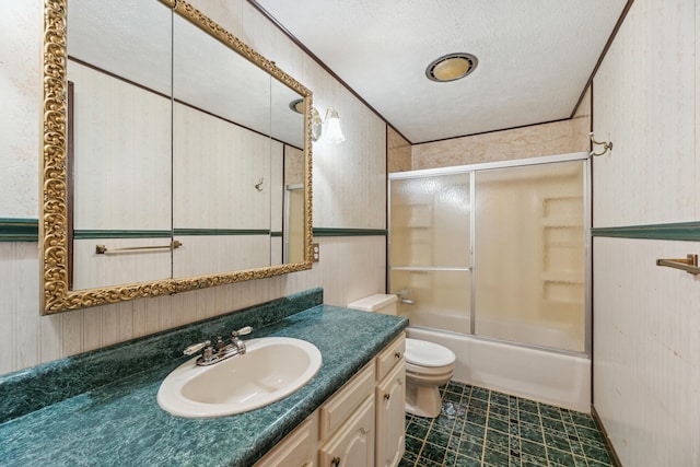 full bath with vanity, toilet, wallpapered walls, bath / shower combo with glass door, and a textured ceiling