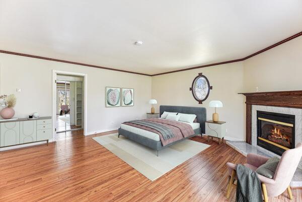 bedroom featuring crown molding, baseboards, a premium fireplace, and light wood-type flooring