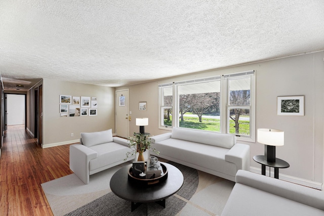 living room featuring dark wood-style flooring, baseboards, and a textured ceiling