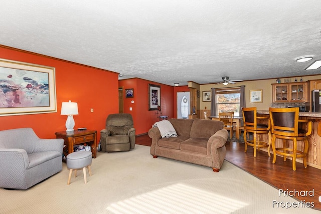 living area with a ceiling fan, bar area, wood finished floors, and a textured ceiling