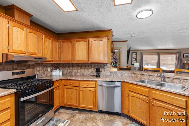 kitchen with under cabinet range hood, a sink, tasteful backsplash, appliances with stainless steel finishes, and light countertops