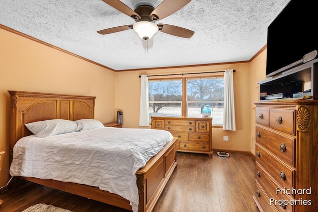bedroom with hardwood / wood-style floors, baseboards, a textured ceiling, and ornamental molding
