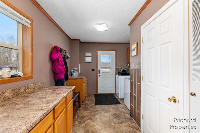 washroom featuring a textured ceiling, crown molding, cabinet space, and washer and clothes dryer