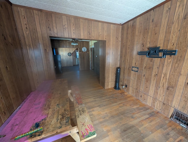 corridor with crown molding, wood finished floors, and wood walls