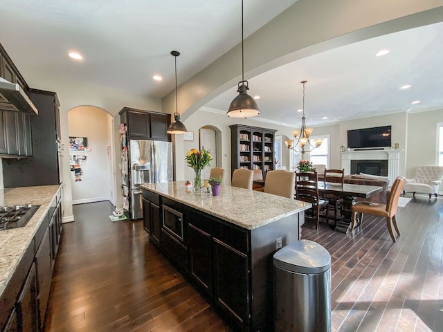 220 S Castell Ave, Rochester, MI 48307 - kitchen featuring arched walkways, stainless steel appliances, dark wood-type flooring, light stone counters, and a center island