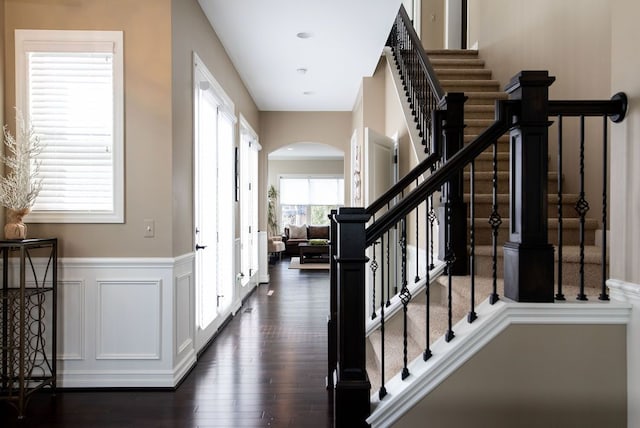 220 S Castell Ave, Rochester, MI 48307 - foyer entrance with arched walkways, stairway, dark wood-style flooring, a wainscoted wall, and a decorative wall