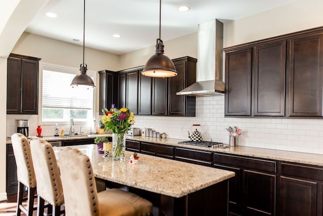 220 S Castell Ave, Rochester, MI 48307 - kitchen featuring wall chimney range hood, stainless steel gas cooktop, a sink, a kitchen bar, and a center island